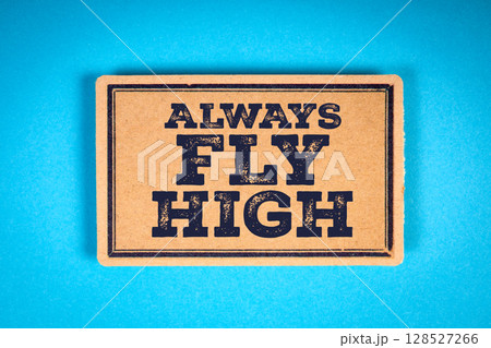 Inspirational Sign with Message Always Fly High on Brown Cardboard over Blue Background 128527266