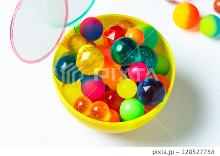 カップに入ったカラフルなスーパーボールとポイ 128527788