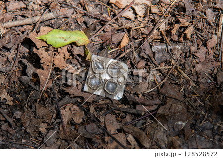 Discarded Empty Pill Blister Pack Littering a Forest Floor 128528572