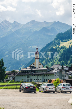 Alpine village with church tower nestled among mountains on sunny summer day. High quality photo Alpine village with church tower nestled among mountains on sunny summer day. High quality photo 128529541