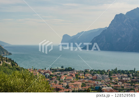 Lake Garda view with mountains and coastal Italian town under bright summer sky. High quality photo 128529565