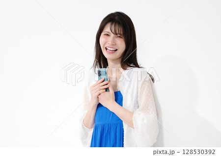 笑顔でスマートフォンを持つ女性 128530392