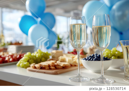 Champagne Glasses and Buffet Table with Blue Balloons on a White Table at Celebration Event Champagne Glasses and Buffet Table with Blue Balloons on a White Table at Celebration Event 128530714