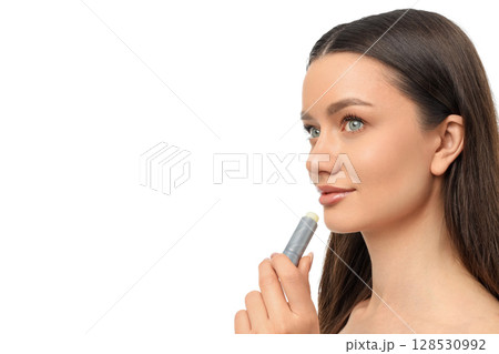 Woman applying lip balm, looking curious, isolated on white, PNG 128530992