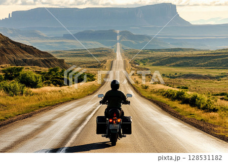 Motorcycle rider on a mountain road surrounded by scenic landscape, symbolizing freedom, adventure, and travel lifestyle 128531182