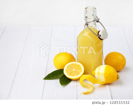 Freshly squeezed lemon juice in bottle and lemons on light background. For vitamin drink or cocktail. Selective focus. Space for text 128531532