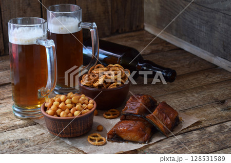 Football fan set with mugs of beer, bottle and salty snacks on wooden background. Junk food for beer or cola. Photographed with natural light. Copy space Football fan set with mugs of beer, bottle and salty snacks on wooden background. Junk food for beer or cola. Photographed with natural light. Copy space 128531589