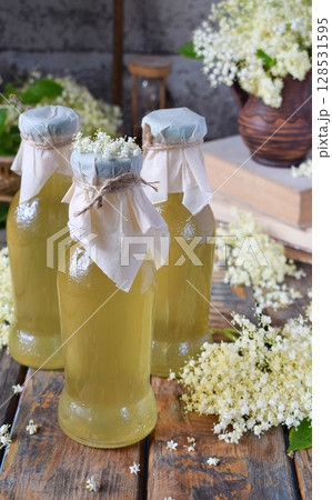Elderflower cordial syrup and blossom flower in wooden background. Edible elderberry flowers add flavour and aroma to drink and dessert. Copy space. 128531595
