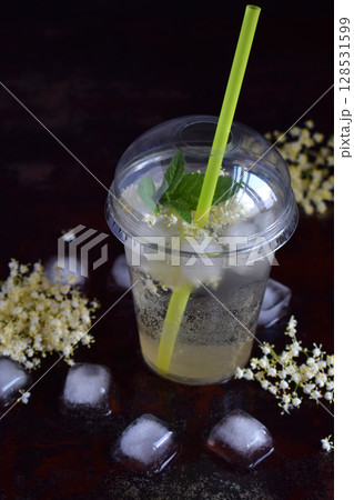 Homemade elderflower lemonade with lemon and elderberry flowers in plastic cup with sphere dome cap and cocktail tube. Elderflower cordial. Summer cold drink 128531599