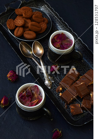 Floral tea made from rose petals and cookies on a dark gray concrete background. Tea drinking in eastern style. Romantic breakfast for Valentine's Day, Women's Day, Mother's Day 128531707
