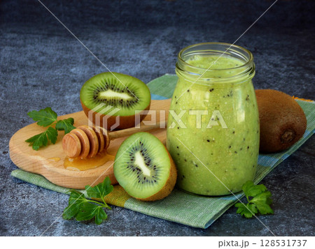 healthy green smoothies from kiwi, oatmeal, nuts and honey on dark background. healthy green smoothies from kiwi, oatmeal, nuts and honey on dark background. 128531737