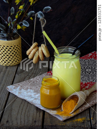 Turmeric powder, paste and latte on wooden background. Ayurvedic healthy golden drink with coconut milk and ghee for beauty and health. Selective focus. Copy space 128531751