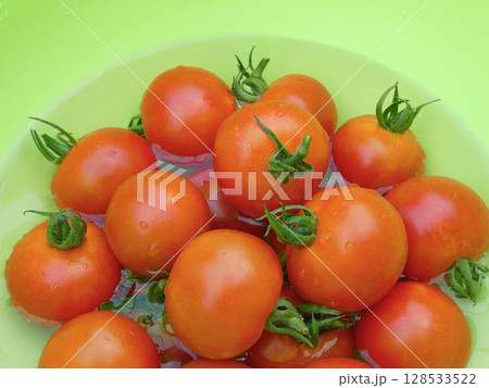 赤く熟した中玉トマトを、水を張った黄緑色ボールで冷やす色あざやかな写真 赤く熟した中玉トマトを、水を張った黄緑色ボールで冷やす色あざやかな写真 128533522