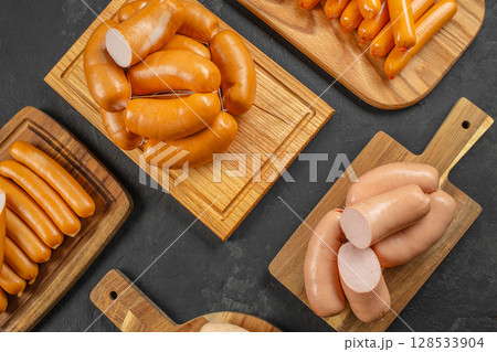 Assorted sausages displayed on wooden cutting boards over a dark stone background, showcasing different shapes, sizes, and textures for culinary presentation Assorted sausages displayed on wooden cutting boards over a dark stone background, showcasing different shapes, sizes, and textures for culinary presentation 128533904