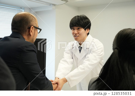 白衣の医者と握手する男性 白衣の医者と握手する男性 128535031