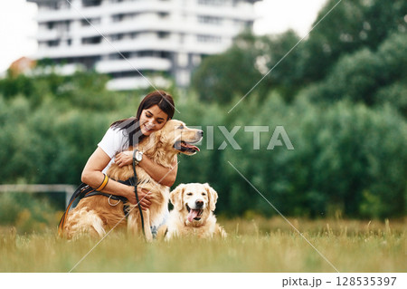 Sitting on the ground. Woman with beautiful dogs are in the field outdoors Sitting on the ground. Woman with beautiful dogs are in the field outdoors 128535397