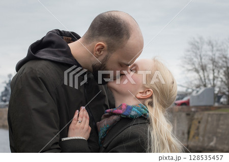 Affectionate man and woman couple hugging each other kissing at seaside 128535457