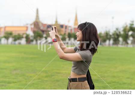 Happy southeast asian woman teenager blogger world explorer on solo travel. Take photo with smartphone. local cultural tourism experience concept in Bangkok, Thailand, Asia 128536622