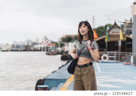 Solo Southeast Asian woman teenager blogger and world travel explorer wait for express boat. local cultural tourism concept on Chao Phraya River in Bangkok Thailand an Asia travel experience Solo Southeast Asian woman teenager blogger and world travel explorer wait for express boat. local cultural tourism concept on Chao Phraya River in Bangkok Thailand an Asia travel experience 128536627