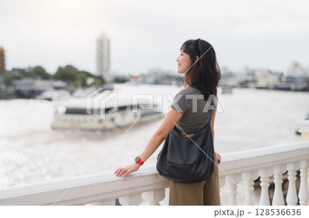 Happy solo Southeast Asian woman teenager blogger world travel tourism. explorer enjoy local cultural experience and wait for express boat Chao Phraya river Bangkok Thailand. Asia concept 128536636