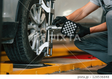 Adjusting the tire. Man is works in the automobile repairing salon Adjusting the tire. Man is works in the automobile repairing salon 128536848