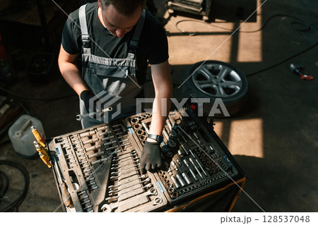 Tools for the repair in the box. Man is works in the automobile salon Tools for the repair in the box. Man is works in the automobile salon 128537048