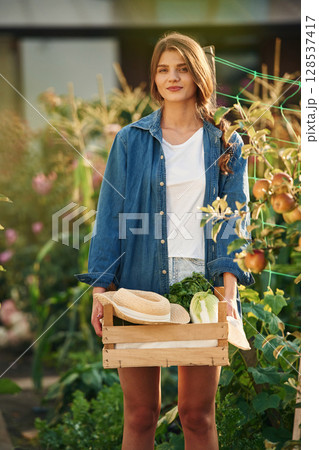 Confident worker with wooden box. Beautiful young woman is gardening Confident worker with wooden box. Beautiful young woman is gardening 128537417