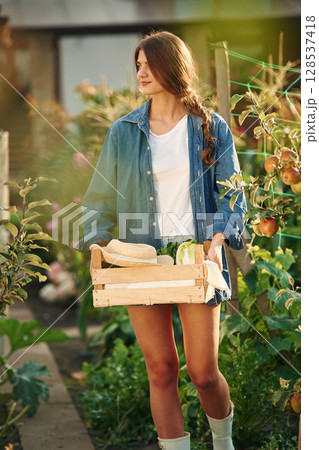 Confident worker with wooden box. Beautiful young woman is gardening Confident worker with wooden box. Beautiful young woman is gardening 128537418