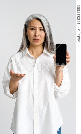 スマートフォンを手に怒った表情をしている女性 128537809