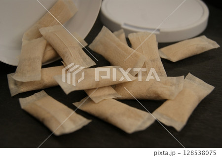 Packaging and nicotine nicotine pouches on a dark background. Close-up. 128538075
