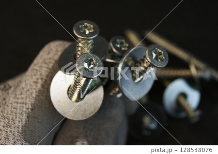 Construction work process. Construction worker holding large bolts with washers.  128538076