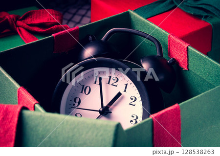 Waiting for the new year. Clock with an alarm clock and a gift. 128538263