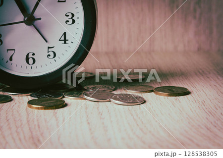 Alarm clock and money. Time is money. Coins on the background of the clock. Alarm clock and money. Time is money. Coins on the background of the clock. 128538305