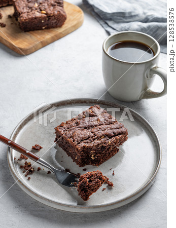 Chocolate brownie on a plate on a light background with cup of freshly brewed coffee and napkin. Chocolate brownie on a plate on a light background with cup of freshly brewed coffee and napkin. 128538576