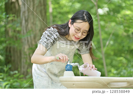 水筒に水を入れる若い女性 128538849