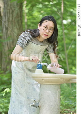 水筒に水を入れる若い女性 128538851