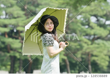 日傘をさして散歩する若い女性 128538889