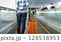 空港の動く歩道に乗る女性 128538953