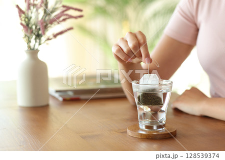 Woman hand prepating tea with a bag at home Woman hand prepating tea with a bag at home 128539374