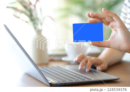 Woman hand showing blank card using laptop 128539376