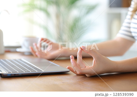Woman hands with a laptop relaxing doing yoga Woman hands with a laptop relaxing doing yoga 128539390