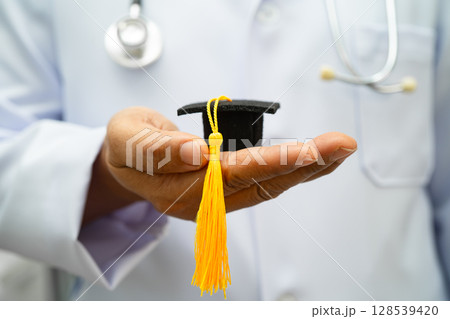 Asian woman doctor holding graduation hat in hospital, Medical education. 128539420