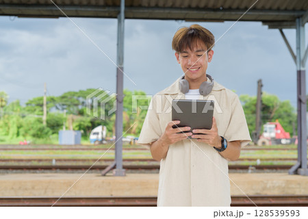 Young non binary tourist traveler in train station using digital tablet computer Young non binary tourist traveler in train station using digital tablet computer 128539593