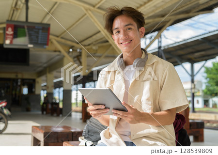 Young non binary tourist traveler in train station using digital tablet computer Young non binary tourist traveler in train station using digital tablet computer 128539809
