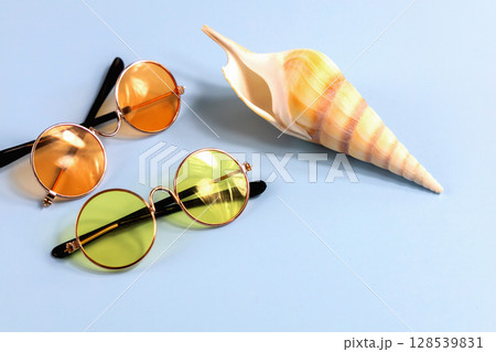 Large sea shell and sunglasses on blue background 128539831