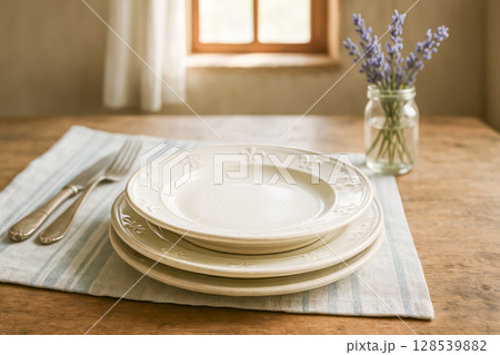 Ceramic Plates Stacked On Rustic Wooden Table With Cutlery And Lavender For Dinnerware Branding And Dishware Advertising Visuals. Concept Of Country French Style Dining, Kitchen Collection Promotion 128539882