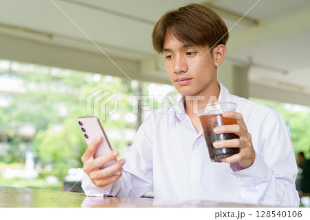 Non binary university student sitting in college campus Non binary university student sitting in college campus 128540106