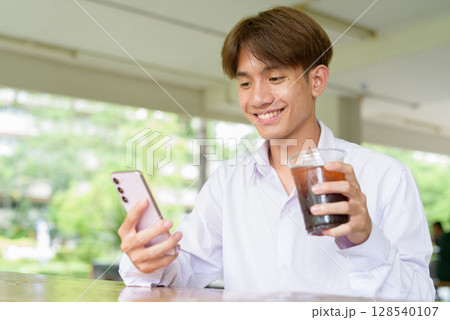 Non binary university student sitting in college campus Non binary university student sitting in college campus 128540107
