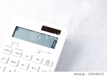 白いテーブルの上に置かれた、白い電卓 白いテーブルの上に置かれた、白い電卓 128540153