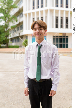 Happy non binary university student smiling in college campus 128540209